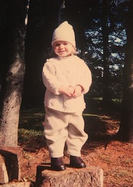 Une jeune Coralie vêtue d'une tenue entièrement blanche et debout sur une bûche